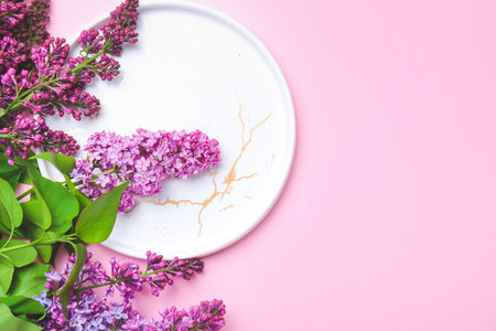 Beautiful lilac flowers ad empty plate on color backgroundの写真素材