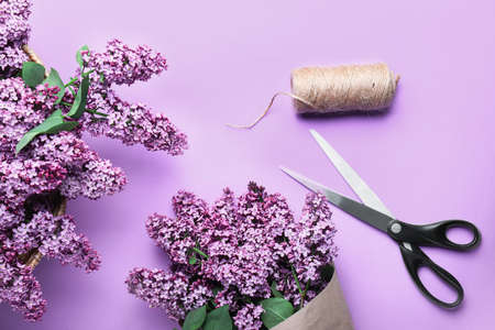 Beautiful lilac flowers and scissors on color backgroundの写真素材