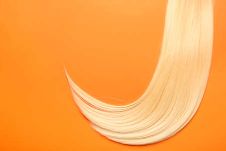 Beautiful long blonde hair on color background
