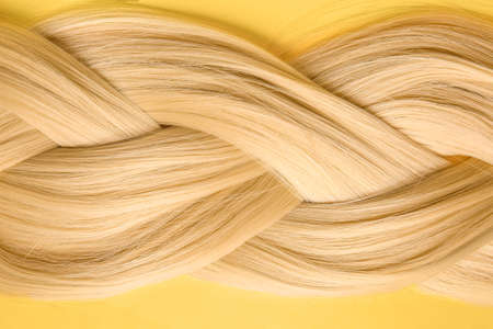 Beautiful braided blonde hair on color background, closeupの写真素材