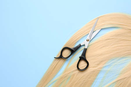 Long blonde hair and scissors on color backgroundの写真素材