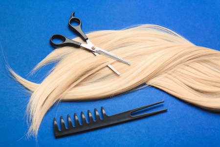 Long blonde hair, comb and scissors on color backgroundの写真素材