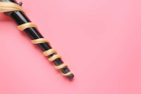 Long blonde hair and curling iron on color backgroundの写真素材