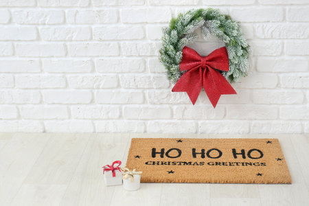 Door mat near wall with Christmas wreathの写真素材