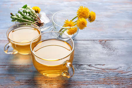 Cups of healthy dandelion tea on color wooden backgroundの写真素材