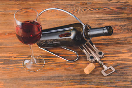 Holder with bottle and glass of wine on tableの写真素材