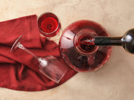 Pouring of wine from bottle into decanter on table