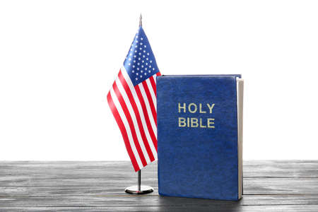 Holy Bible and USA flag on table against white backgroundの写真素材