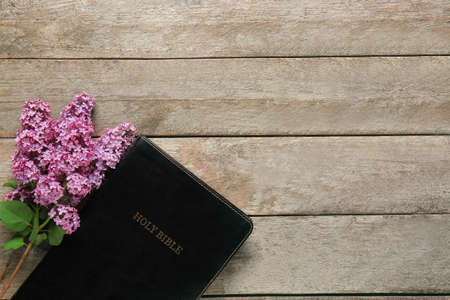 Holy Bible and flowers on wooden background