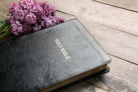 Holy Bible and flowers on wooden background