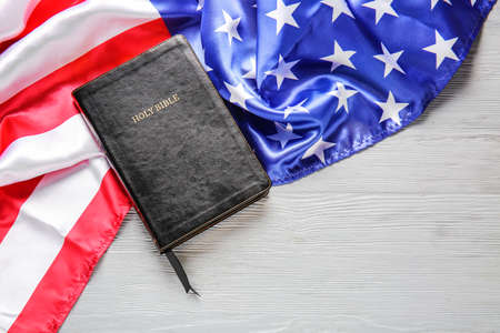 Holy Bible and USA flag on wooden background