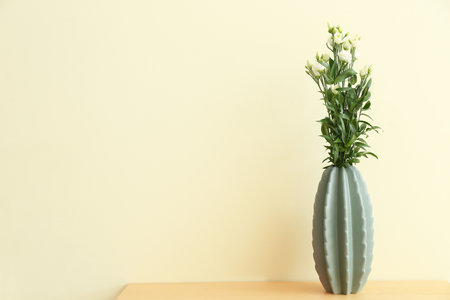 Vase with beautiful flowers on table near color wallの写真素材