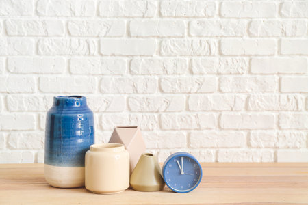 Vases with clock on table near white brick wallの写真素材
