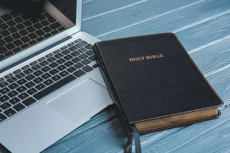 Holy Bible and laptop on table