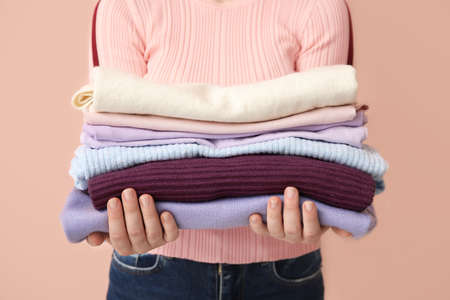 Woman with stack of clean clothes on color background, closeupの写真素材