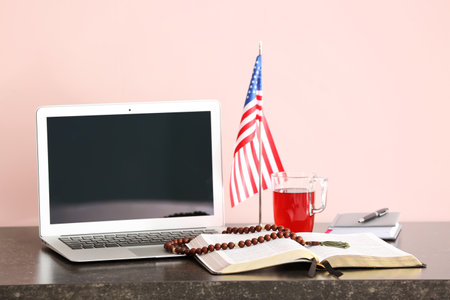 Holy Bible, laptop and USA flag on tableの写真素材