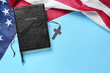 Holy Bible, cross and USA flag on color background