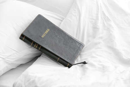 Holy Bible on bed in roomの写真素材