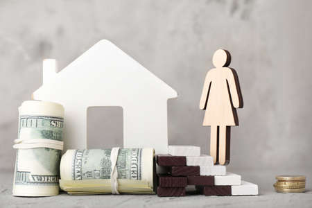 Figures of woman, house and money on table. Concept of debtの写真素材