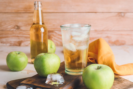 Glass of cold apple cider on table