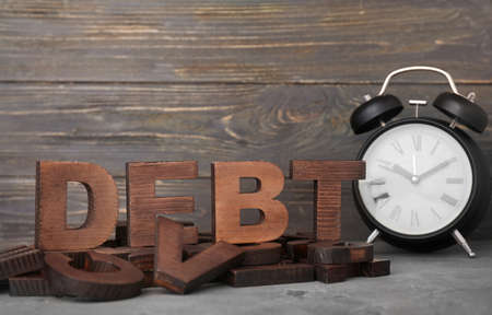Word DEBT and alarm clock on tableの写真素材