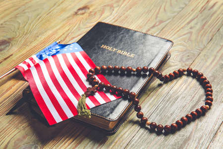 Holy Bible, USA flag and rosary beads on wooden backgroundの写真素材