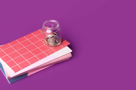 Notebooks and jar with coins on color background. Concept of debt