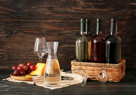 Decanter of wine with bottles and cheese on tableの写真素材