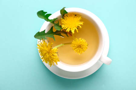 Cup of healthy dandelion tea on color background