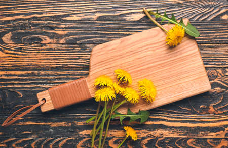 Board and beautiful dandelions on wooden background