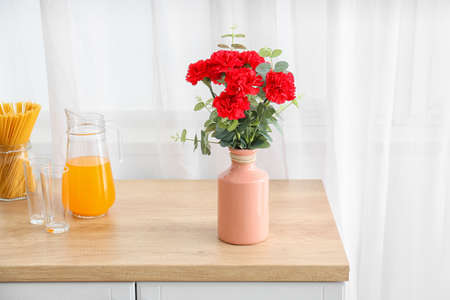 Vase with bouquet of beautiful carnation flowers on table in kitchenの写真素材