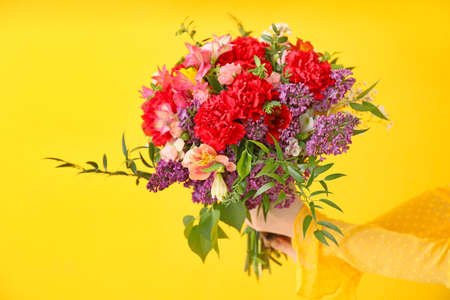 Female hands with beautiful bouquet on color backgroundの写真素材
