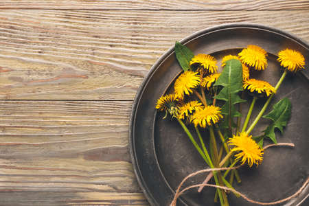 Plate with beautiful dandelions on wooden backgroundの写真素材