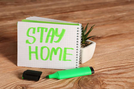 Notebook with text STAY HOME on wooden backgroundの写真素材