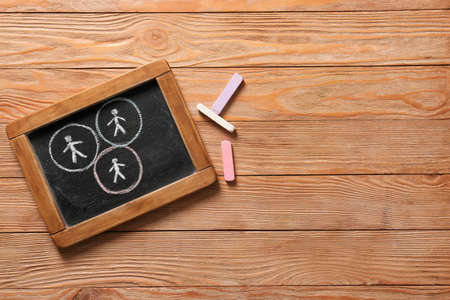 Chalkboard with drawn human figures on wooden background. Concept of social distanceの写真素材