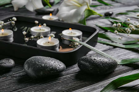 Spa stones and plate with water and candles on dark wooden background. Zen conceptの写真素材