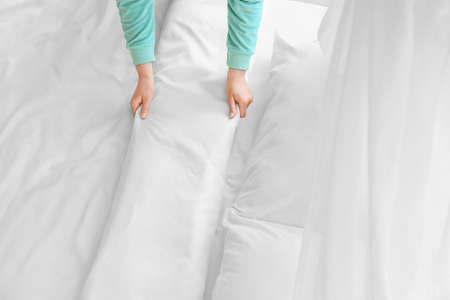 Woman making bed at home