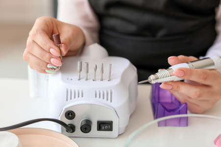 Manicure master working with modern milling cutter in beauty salon, closeupの写真素材
