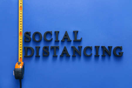 Tape measure with text SOCIAL DISTANCING on color background