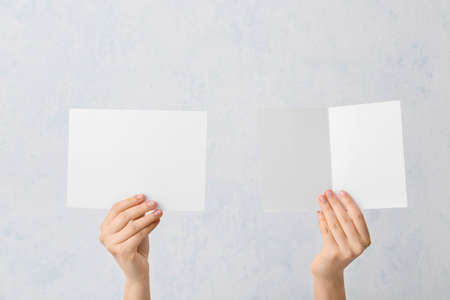 Female hands with blank cards on light backgroundの写真素材