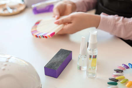 Bottles with cosmetics and nail file on table in beauty salon