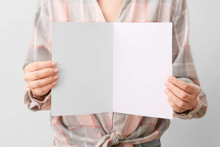 Woman with blank card on light backgroundの写真素材