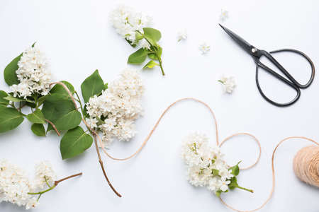 Beautiful lilac flowers, thread and scissors on white backgroundの写真素材