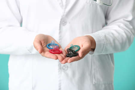 Female gynecologist with condoms on color background, closeupの写真素材
