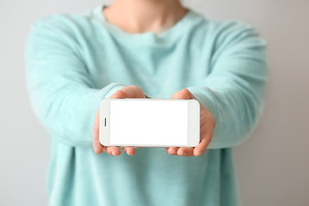 Woman with mobile phone on light backgroundの写真素材