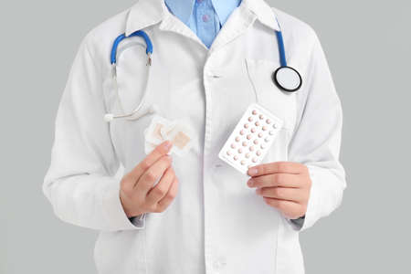 Female gynecologist with different contraceptives on white background, closeup