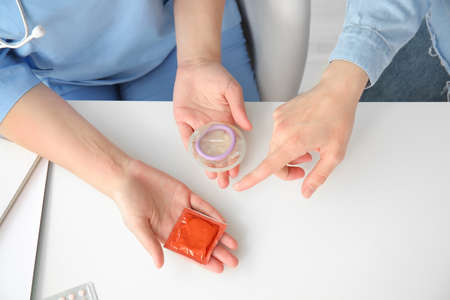 Female gynecologist and patient with condoms in clinic, top viewの写真素材