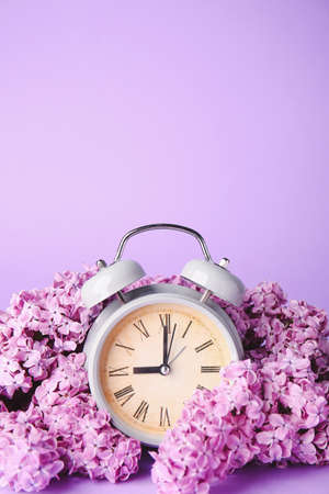 Alarm clock and flowers on color background. Spring timeの写真素材