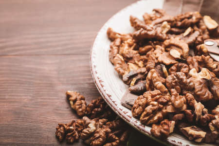 Plate with tasty walnuts on wooden backgroundの写真素材