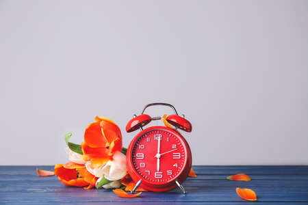 Alarm clock and flowers on table. Spring time